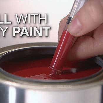 Hand with pen in paint bucket, filling it, syringe-like