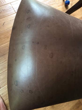 A reviewer's before: leather barstool dark with age and dirt, with several water spots 
