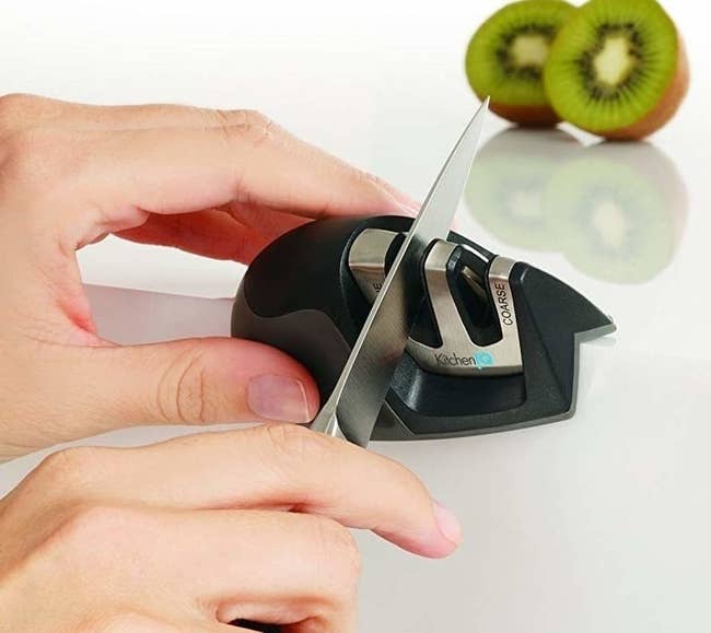 hands holding the two-slot sharpener on the corner of a counter (as designed), pulling a knife through