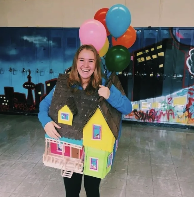 Someone dressed as the colorful house from &quot;Up&quot; with balloons attached to them