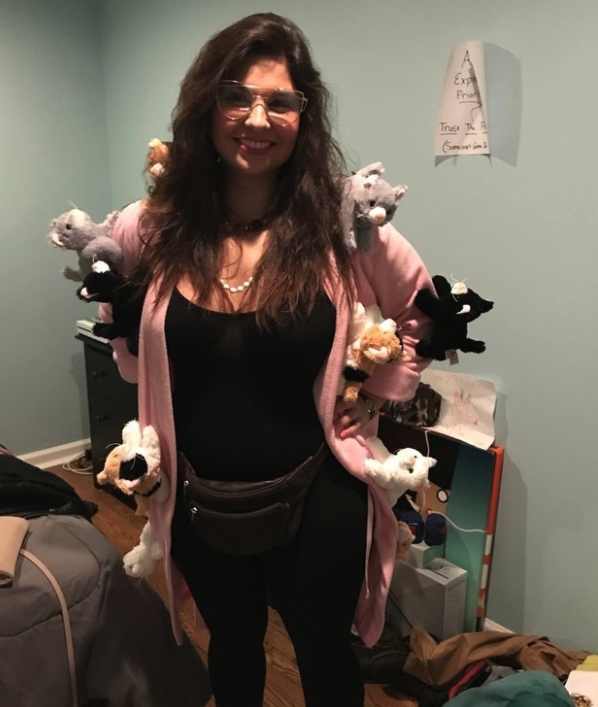 Someone dressed in a rob with a dozen stuffed animal cats attached to them