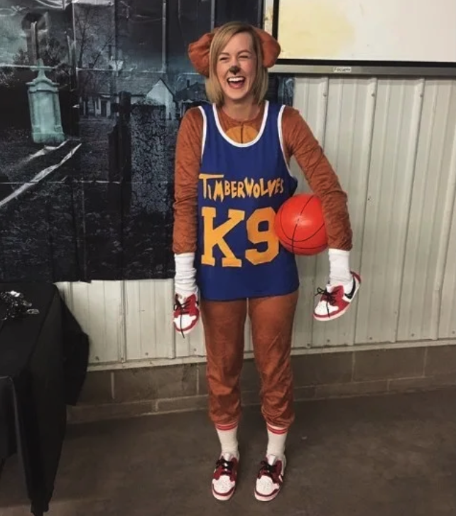 Someone in a dog onesie while wearing a basketball jersey