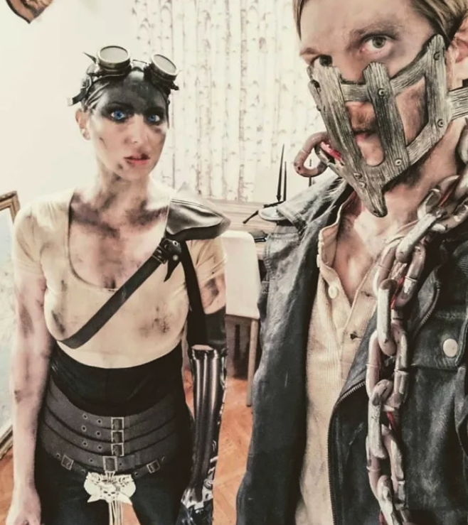 Two people dressed as dirty and apocalyptic characters from &quot;Fury Road,&quot; with chains and grey clothes