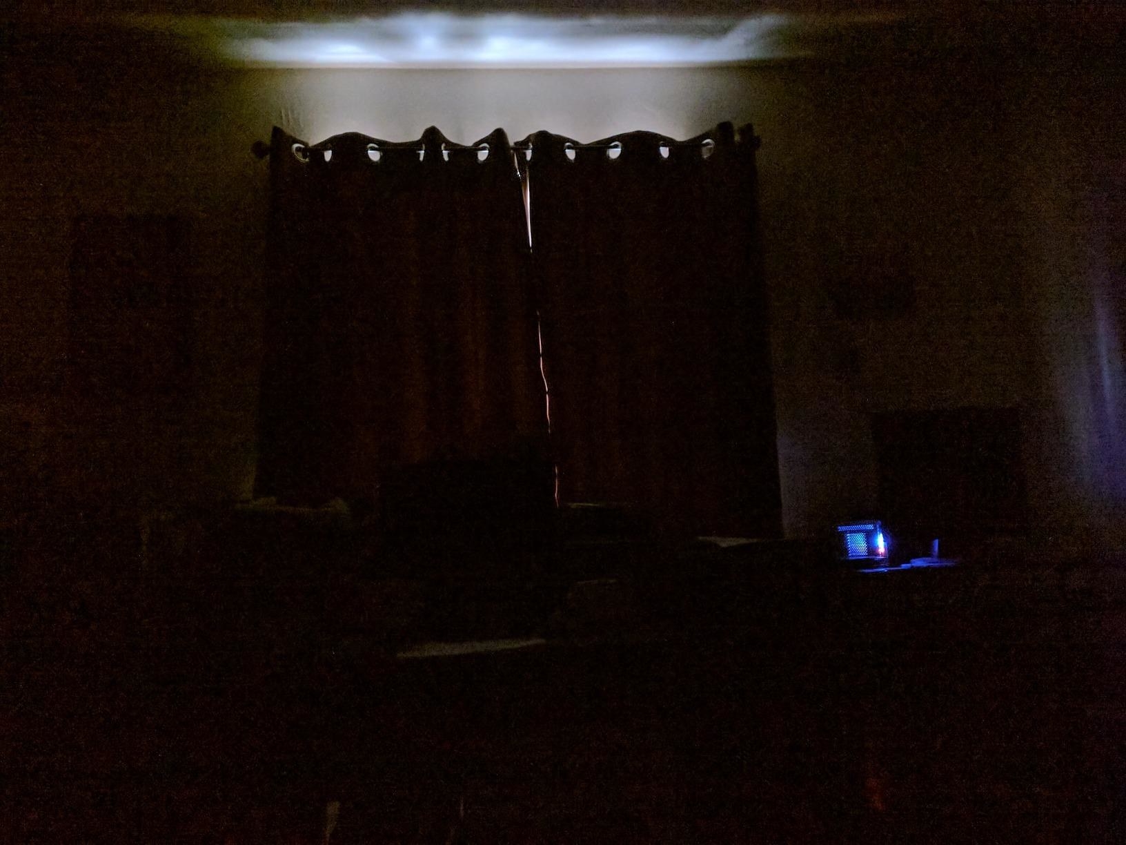 Reviewer&#x27;s dark room with blackout curtains; only a very thin line between the curtains and the light that comes in from the gab above the curtains is visible