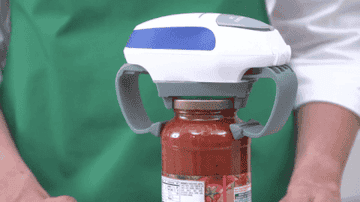 a moving gif of the jar opener clamped onto a jar of sauce, opening the lid