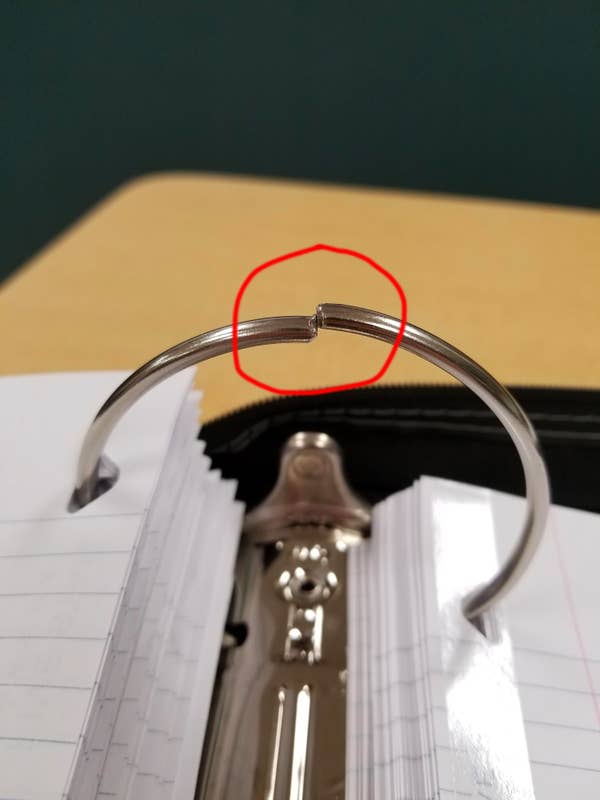 Open binder with misaligned metal rings, causing papers to snag. Red circle highlights the gap in the rings