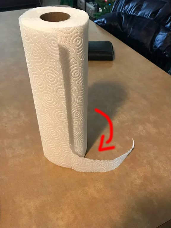 Roll of paper towels on a table with a red arrow indicating the direction to pull the towel