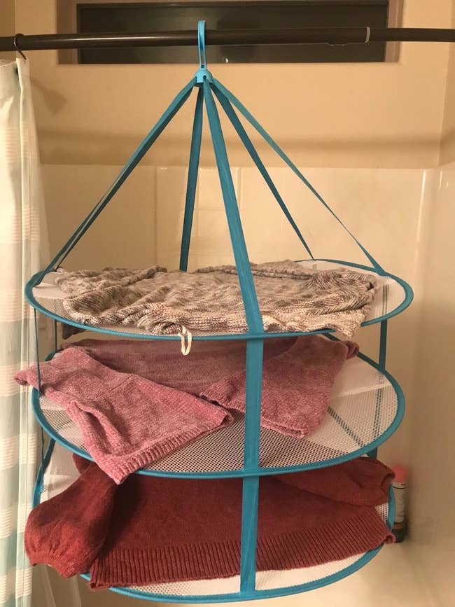 The rack, with three sweaters, on another reviewer's shower curtain rod