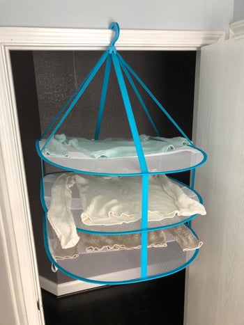 The rack hanging in a reviewer's doorway from the top of the molding; three sweaters sit drying