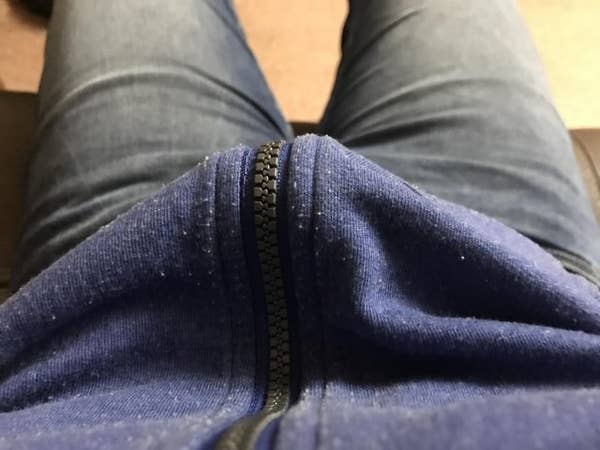 View of a person wearing a blue zip-up hoodie and blue jeans, seated