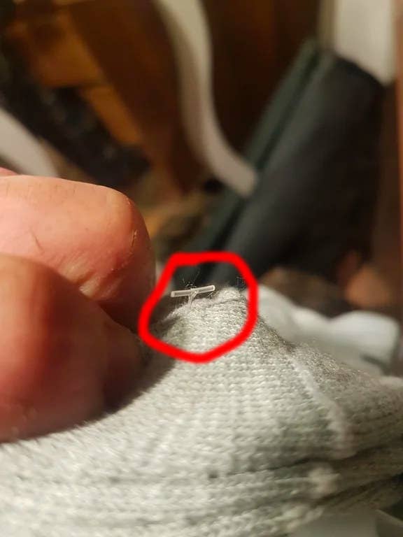 Close-up of a needle stuck in grey fabric, highlighted with a red circle