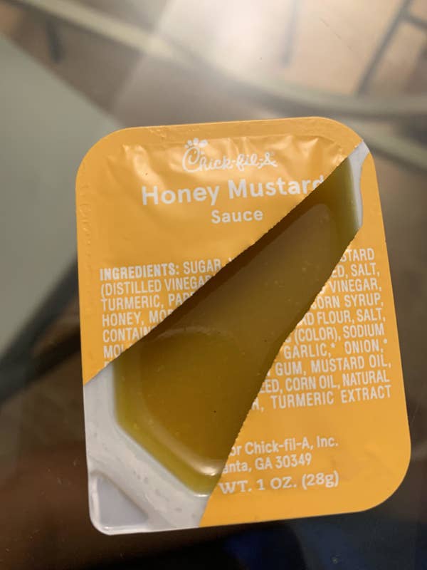 Chick-fil-A Honey Mustard sauce packet partially opened, showing sauce and labeled ingredients