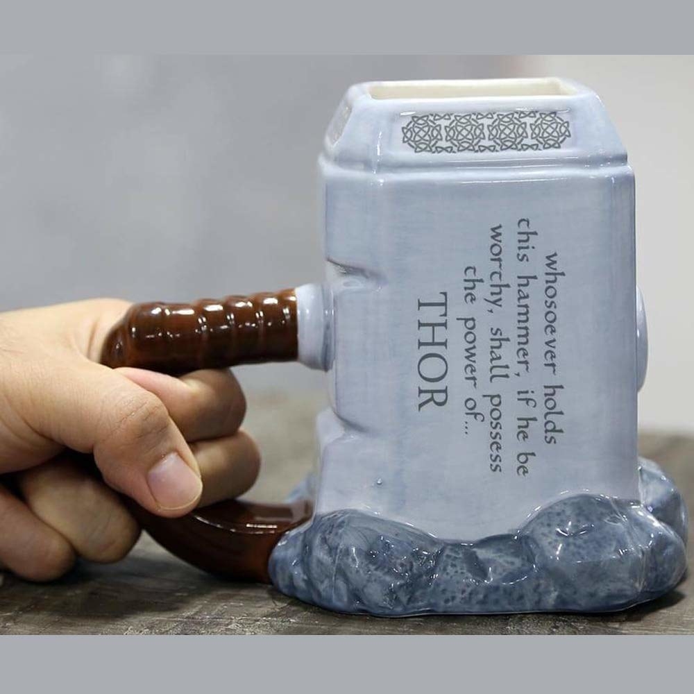 A mug shaped like Mjolnir with the text &#x27;Whosoever holds this hammer, if he be worthy, shall possess the power of....Thor&#x27; written on it.