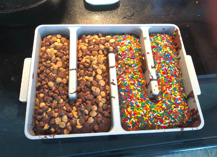 Reviewer&#x27;s homemade brownies baked inside pan with one side covered in peanut butter chocolate chips and the other side with sprinkles 