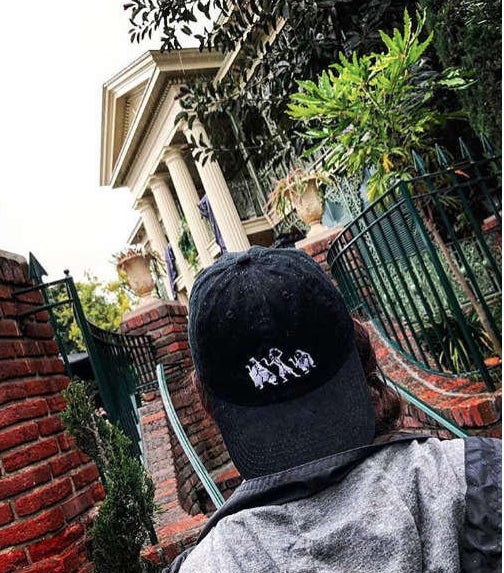 model wearing the haunted mansion dad hat while at disneyland