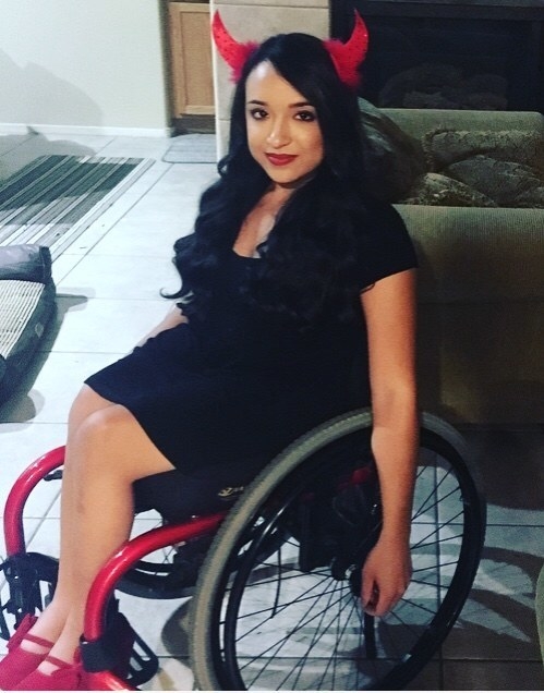 A woman in a wheelchair with devil horns on her head