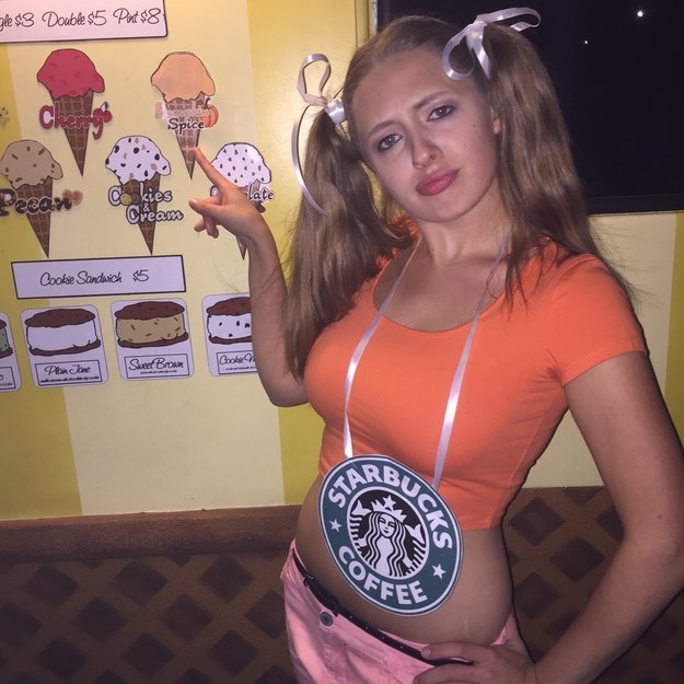 A woman in an orange shirt with pigtails and a large necklace that says &quot;Starbucks&quot;