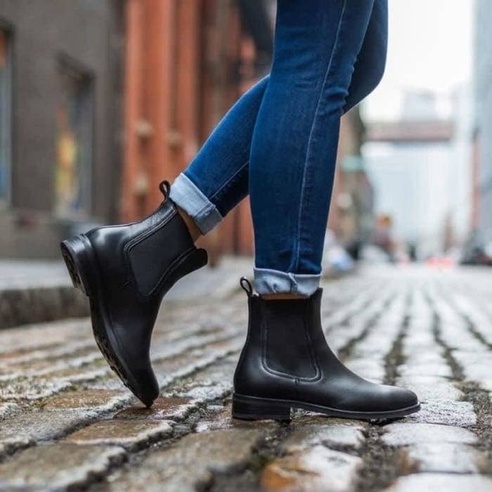 model wearing the black booties while walking on cobblestone