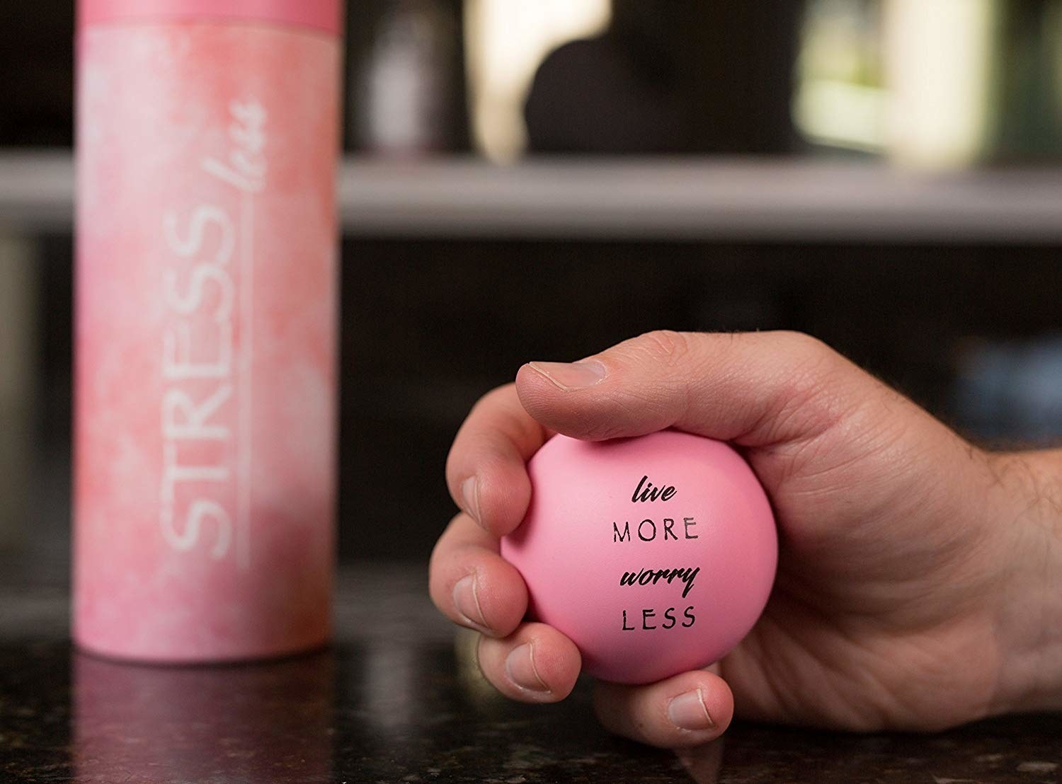 A person squeezing one of the stress balls that says, &quot;live more worry less&quot;