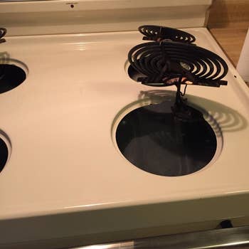 Reviewer photo showing their stovetop after using the drill brush, revealing that it is completely spotless and looks new 