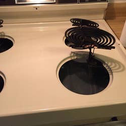 Reviewer photo showing their stovetop after using the drill brush, revealing that it is completely spotless and looks new 