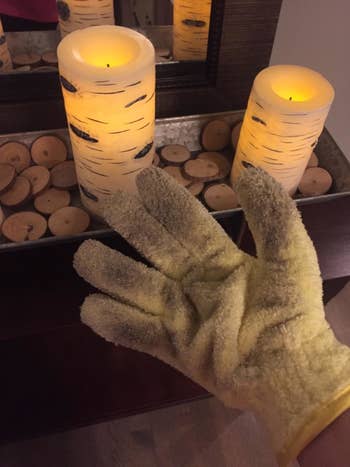 the glove being used to clean around candles on a surface 