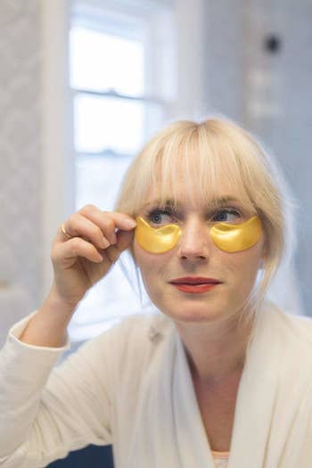 a model placing the gold under eye collagen masks under their eyes