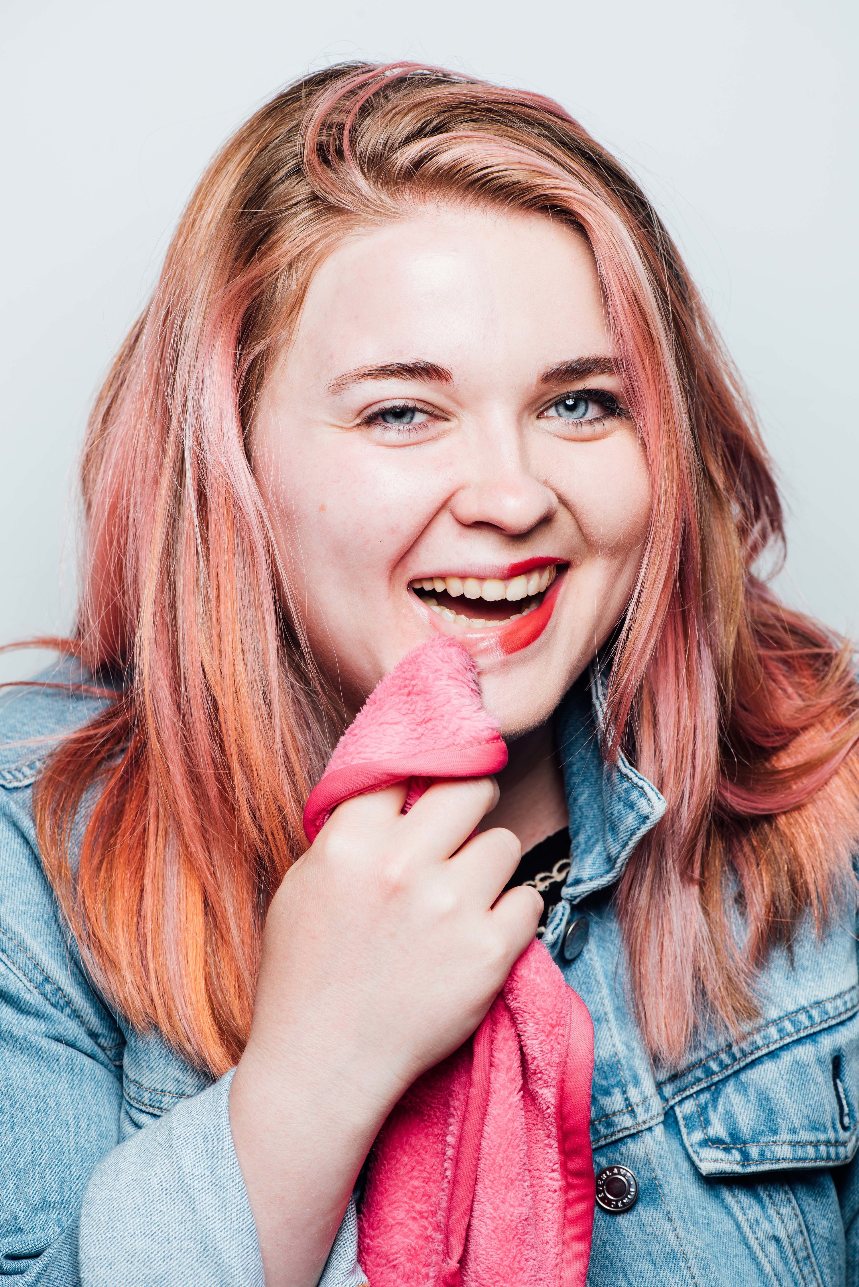 A BuzzFeeder using the pink cloth to wipe makeup off from half of her face  