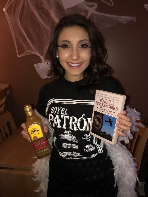 A woman with a tequila shirt, a bottle, a boa, and the &quot;to kill a mockingbird&quot; book