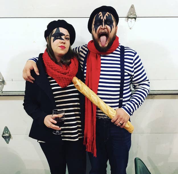 A man and woman with Kiss face paint wearing berets, striped tees, and holding wine and a baguette