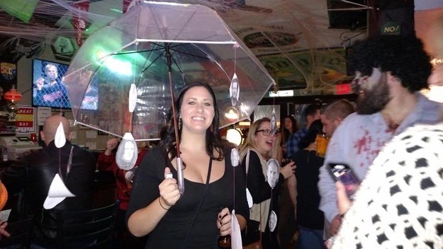 A woman with an umbrella with pictures of men hanging down from strings