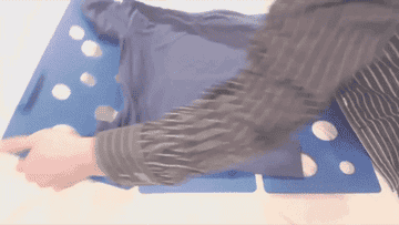 Gif of a person using the square board to quickly fold a t-shirt. It&#x27;s separated into thirds; the two outside thirds fold the sleeves in, then the bottom half of the middle third folds the shirt in half