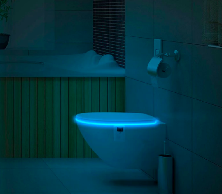 Closed toilet seat glowing from the inside in a dark bathroom 