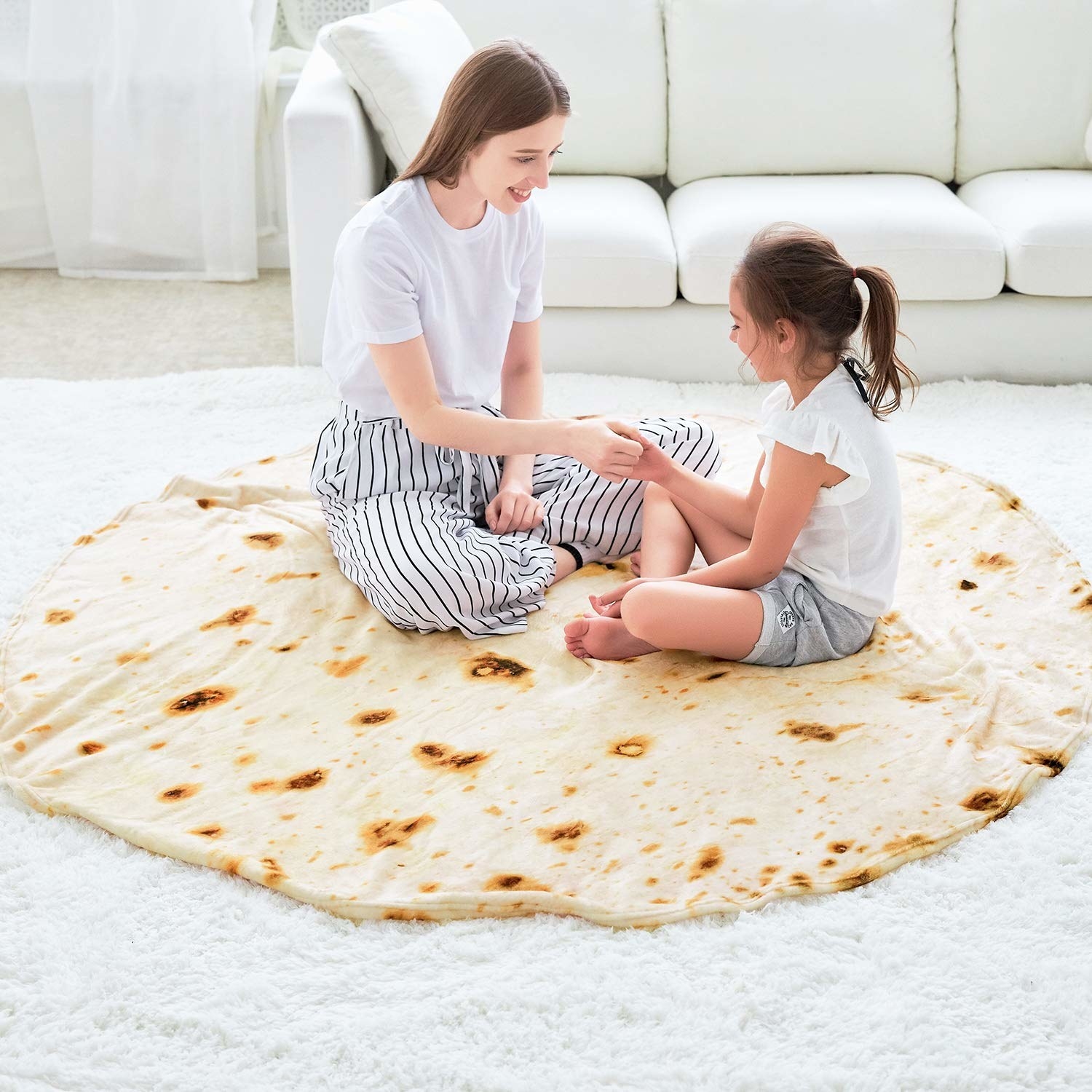 Two people sitting on round tortilla blanket 