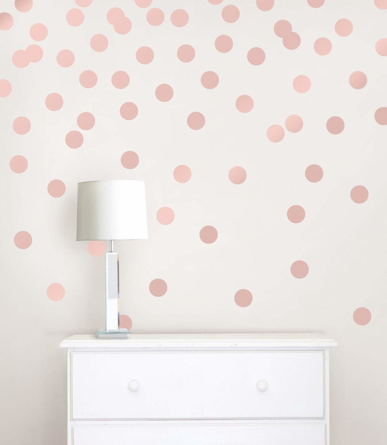 Circular wall decals are stuck on a wall with a set of drawers and a lamp