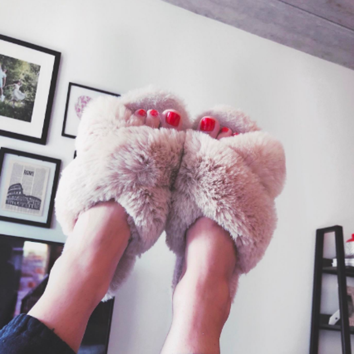 Reviewer holding feet up in fluffy open-toed slippers
