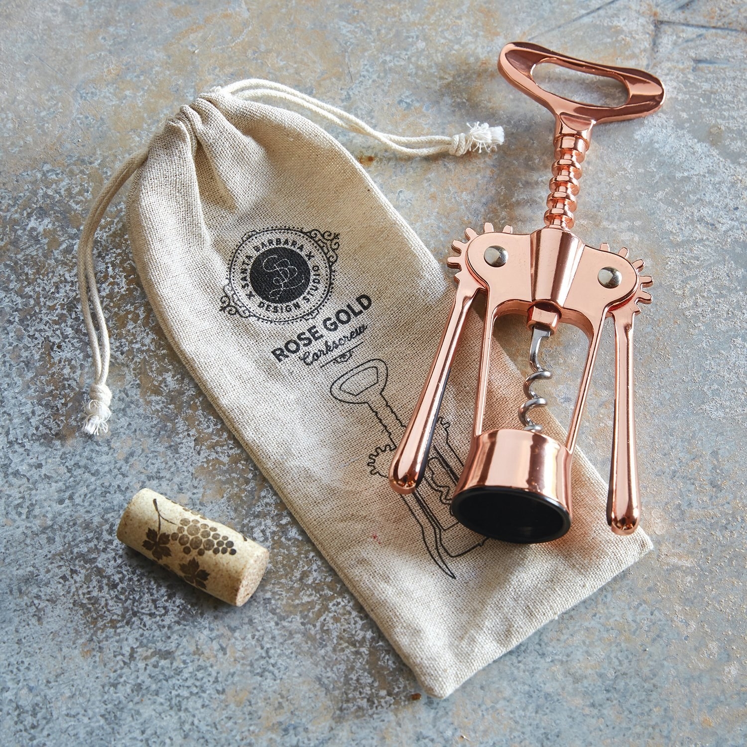 A corkscrew lying flat with a carrying bag and a cork