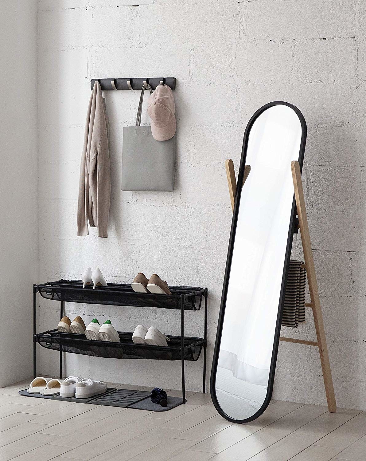A long oval mirror standing at an angle, supported by a ladder back. The ladder has a scarf hanging from it.