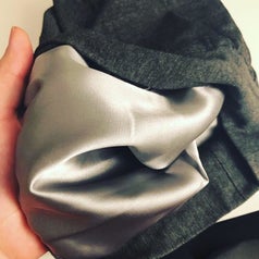 A hand holding the sleep beanie and showing the satin lining.
