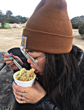 another reviewer eating ramen while wearing the beanie in brown