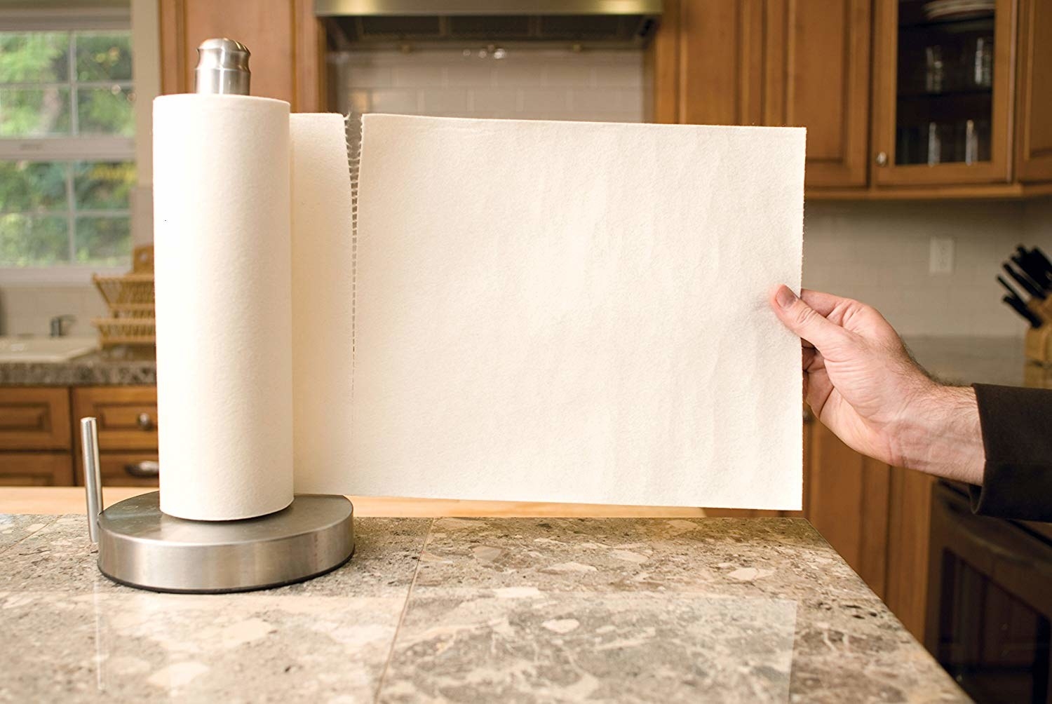 A hand pulling one of the large, thick, square paper towels off the roll
