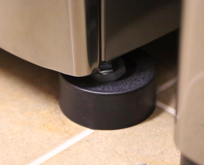 A reviewer&#x27;s photo of the anti-vibration pad placed under a washing machine