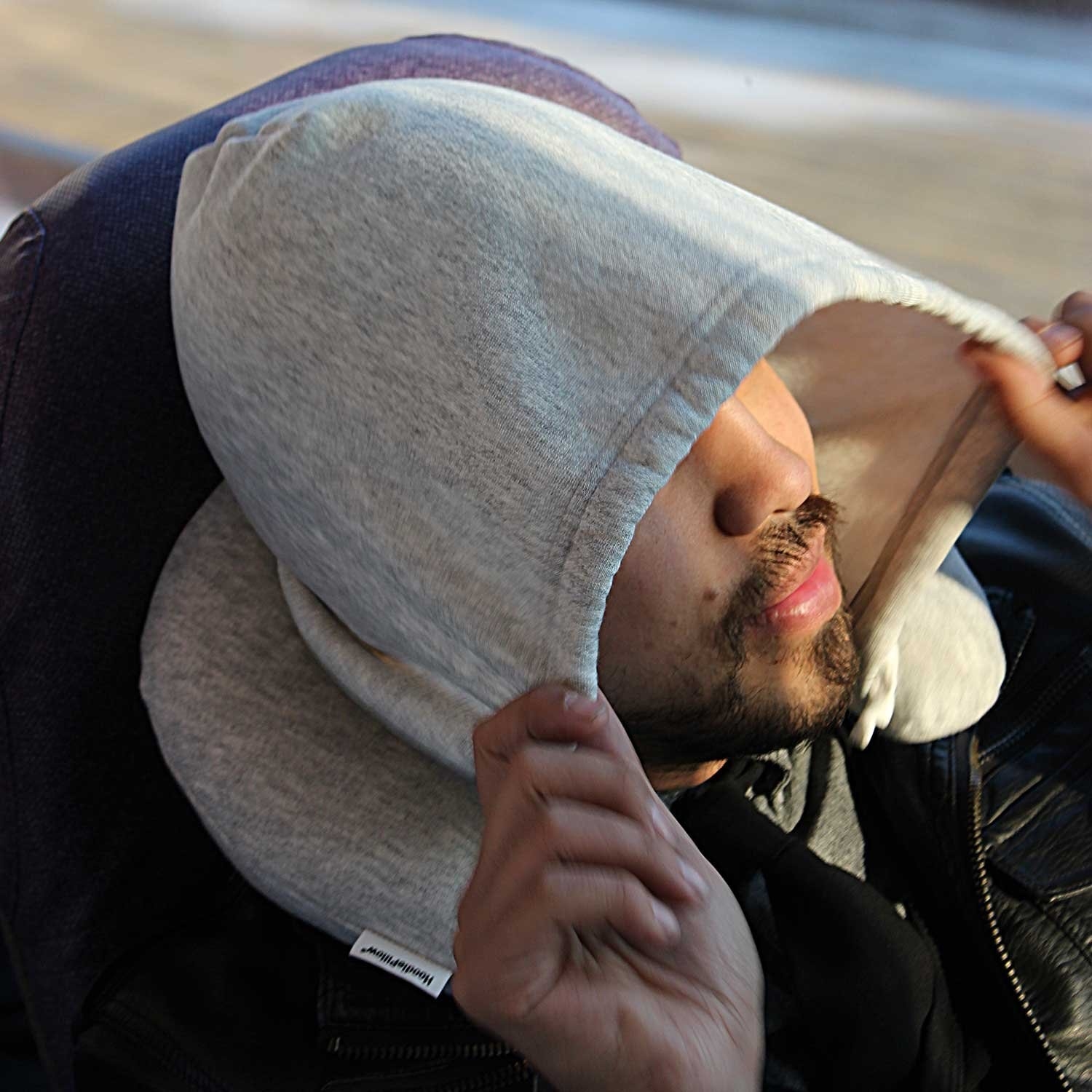 A model using the pillow in grey with the hood up