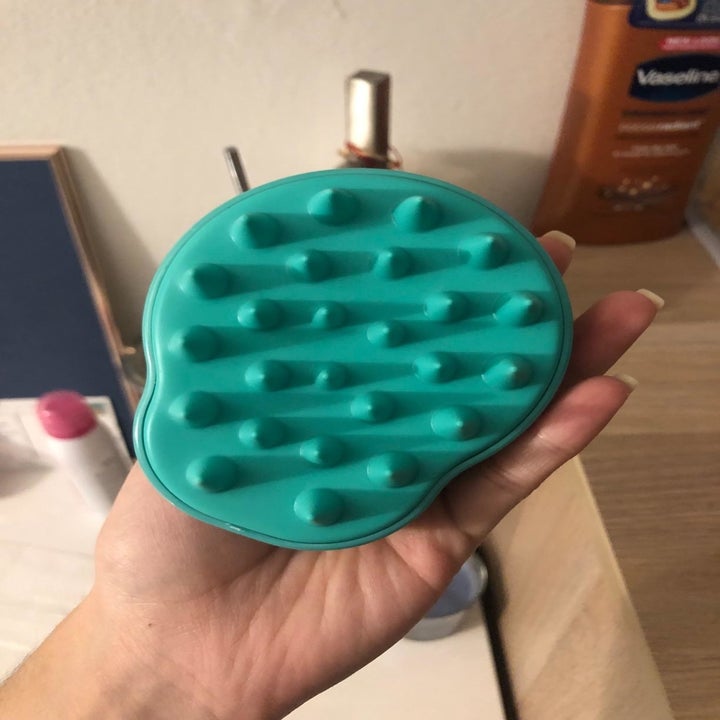 The scalp massager in teal with soft thick silicone bristles