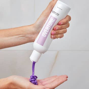 model squeezing purple conditioner in their hands 