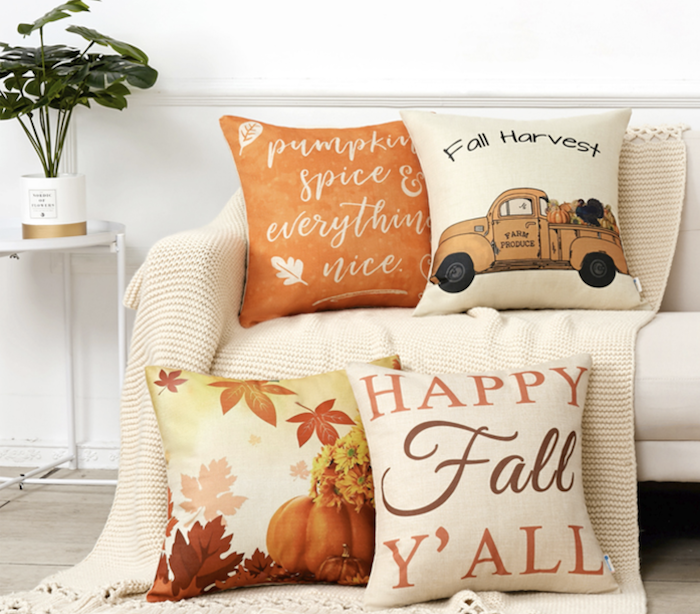 four fall pillows. one is orange and says "pumpkin spice and everything nice." Another says, "Fall Harvest" and has a truck with fall produce on it. Another has pumpkins nad leaves on it. The last pillow says "Happy Fall Y'all."