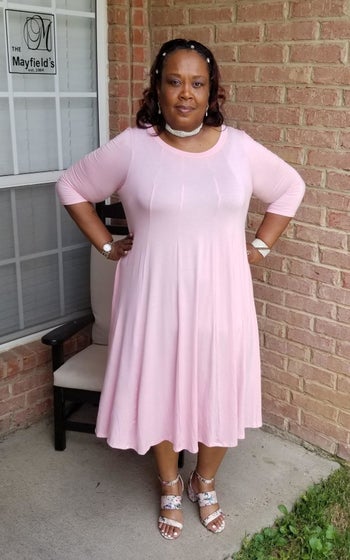 reviewer wearing the dress in pink with heels 
