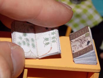 fingers hold a tiny book with leave drawing inside 
