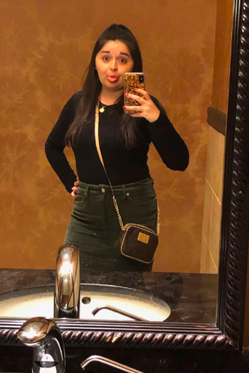 Heather wearing the olive green skirt with a long-sleeve black top and a crossbody bag