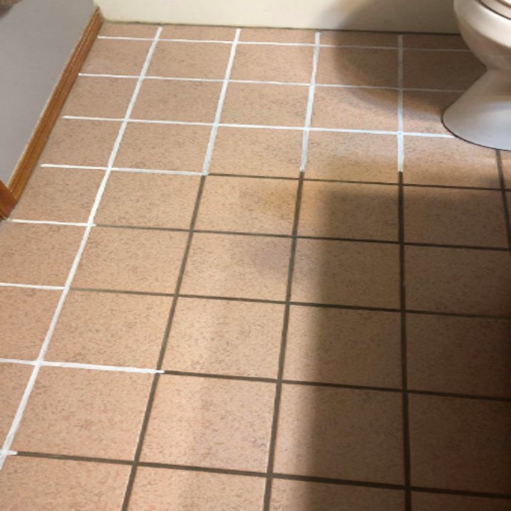 A reviewer's tile partially treated with the product. The original grout is brown and the pen has made it white